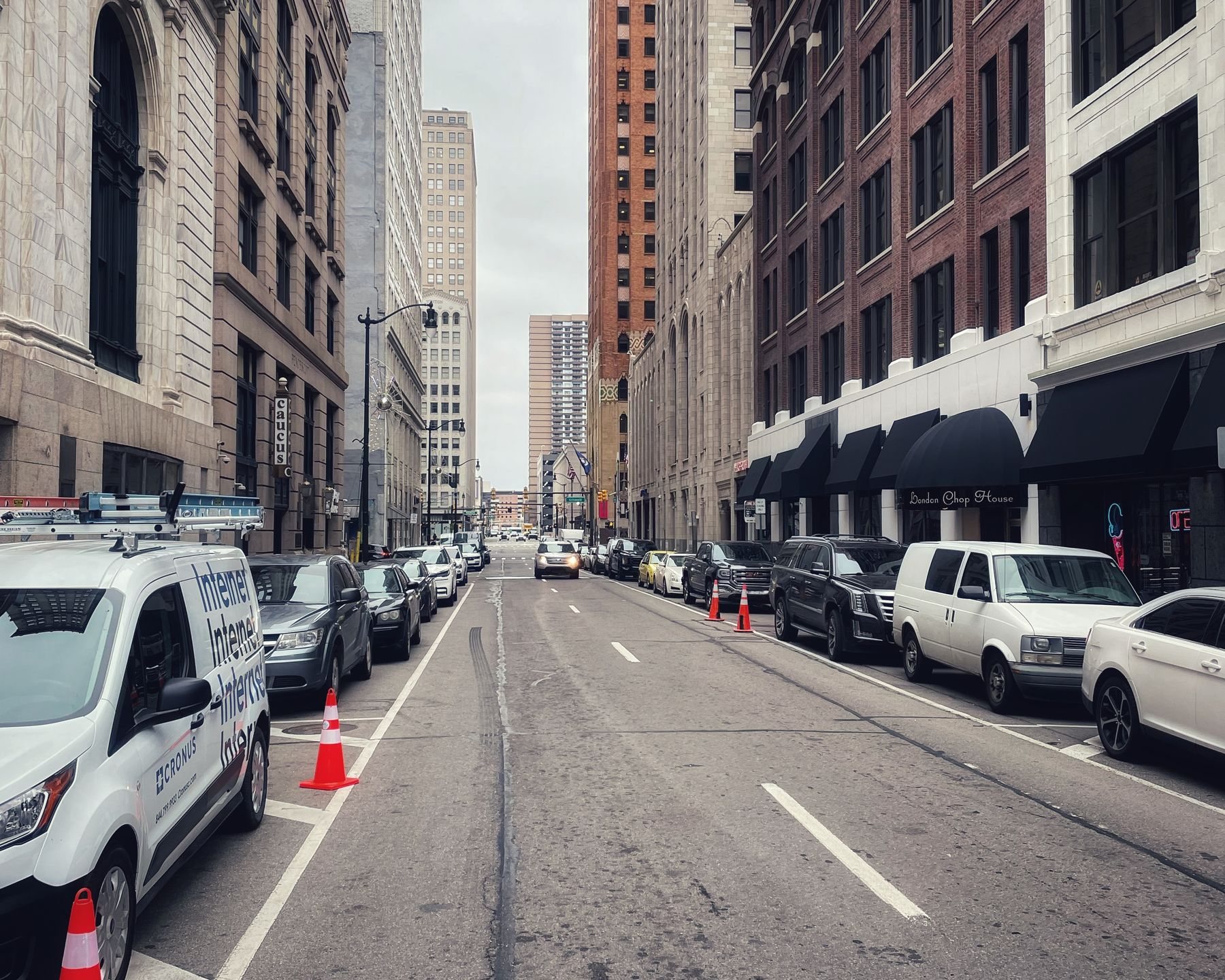 A city street between tall buildings with cars parked on both sides