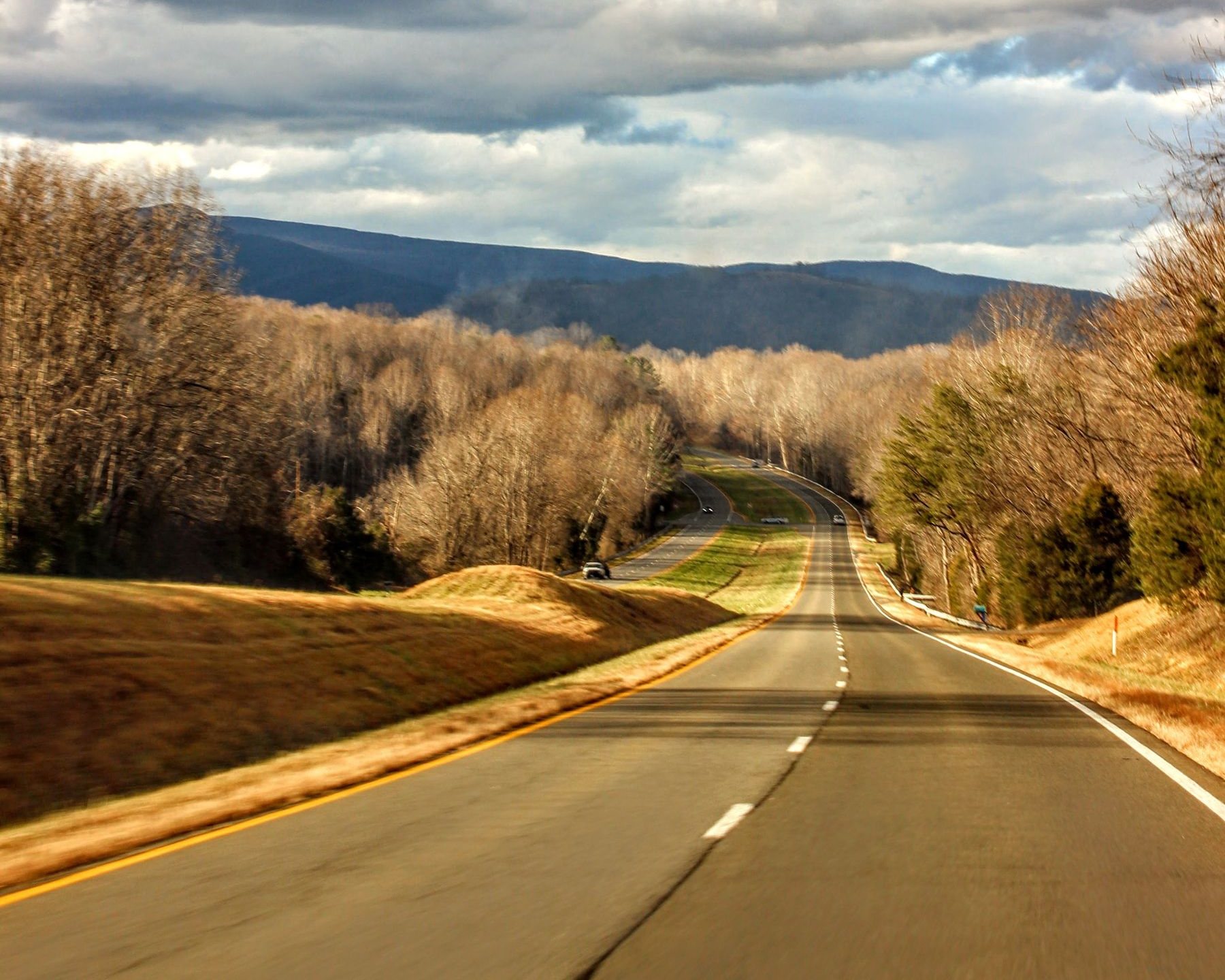 An empty road running through wooded mountains