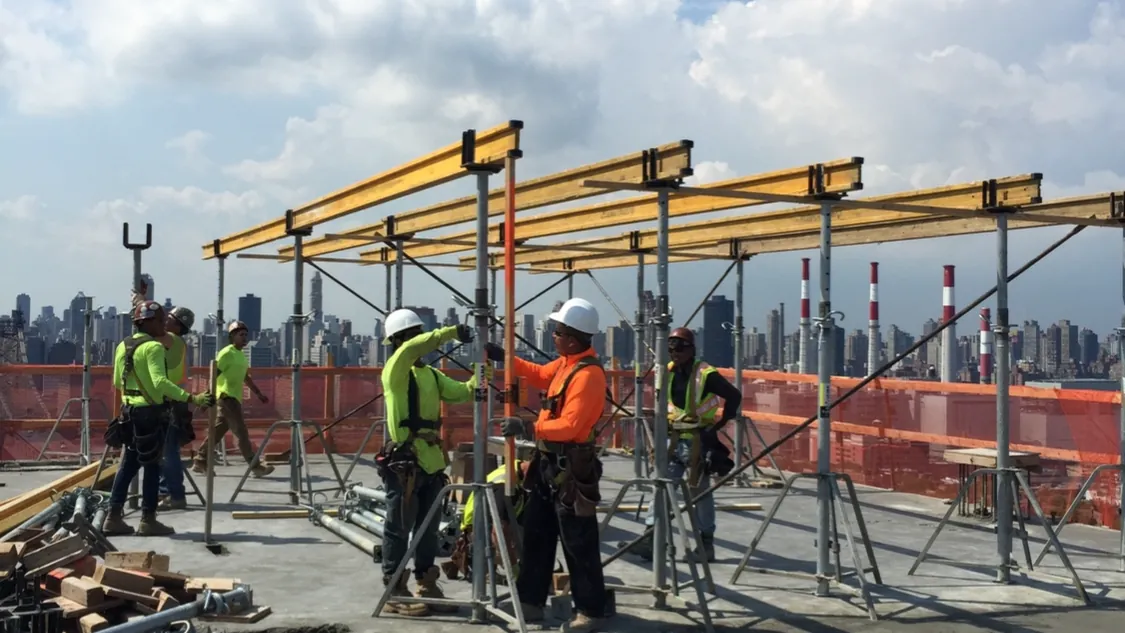 Executive Building Systems crew shoring a rooftop deck with the New York City skyline behind